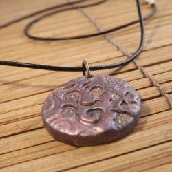 Polymer clay pendant in a circle shape on a leather cord thong, mica powder decoration.